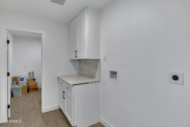 laundry area featuring cabinets, hookup for a washing machine, light hardwood / wood-style floors, and hookup for an electric dryer