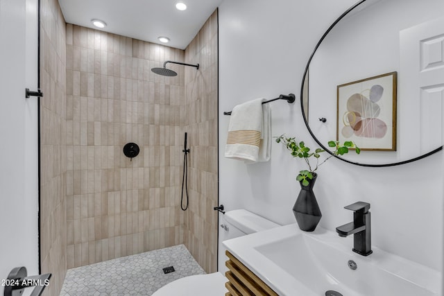 bathroom featuring a tile shower, vanity, and toilet