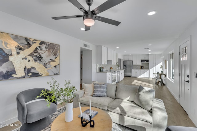 living room with ceiling fan and light hardwood / wood-style flooring