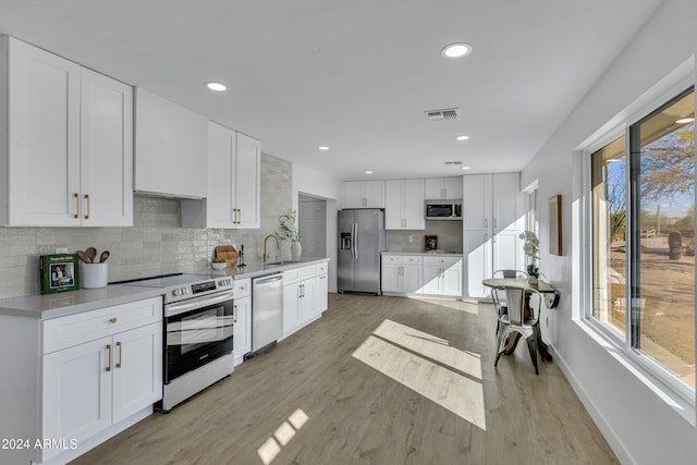 kitchen featuring sink, white cabinets, stainless steel appliances, and light hardwood / wood-style floors