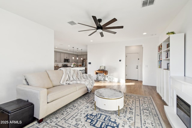 living room with ceiling fan and light hardwood / wood-style floors