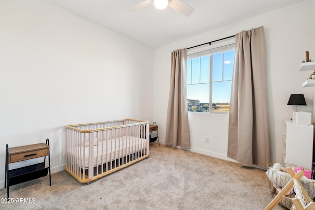 bedroom with a nursery area, ceiling fan, and carpet flooring