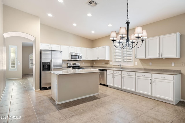 kitchen with hanging light fixtures, sink, vaulted ceiling, appliances with stainless steel finishes, and white cabinetry