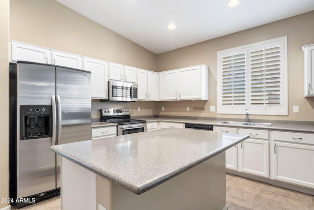 kitchen featuring sink, appliances with stainless steel finishes, a kitchen island, light stone counters, and white cabinetry