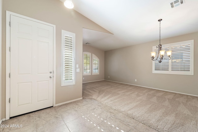 entrance foyer with light colored carpet, lofted ceiling, and a notable chandelier