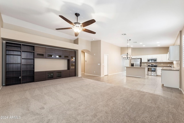 unfurnished living room with sink, light tile patterned floors, and ceiling fan with notable chandelier