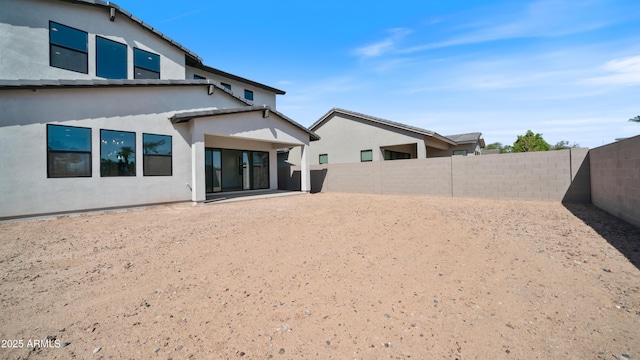 back of house featuring stucco siding and a fenced backyard