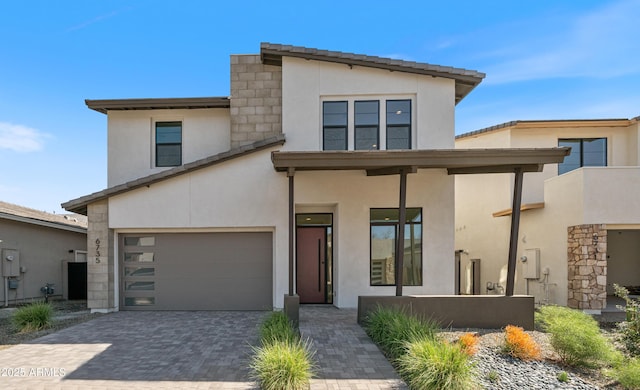 modern home with decorative driveway, a garage, and stucco siding