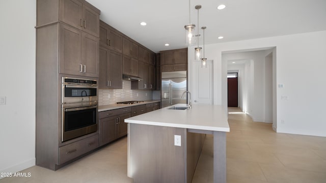 kitchen featuring backsplash, under cabinet range hood, light countertops, stainless steel appliances, and a sink