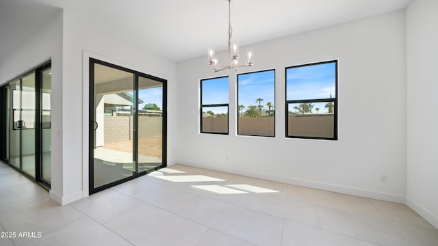 spare room with a notable chandelier and baseboards