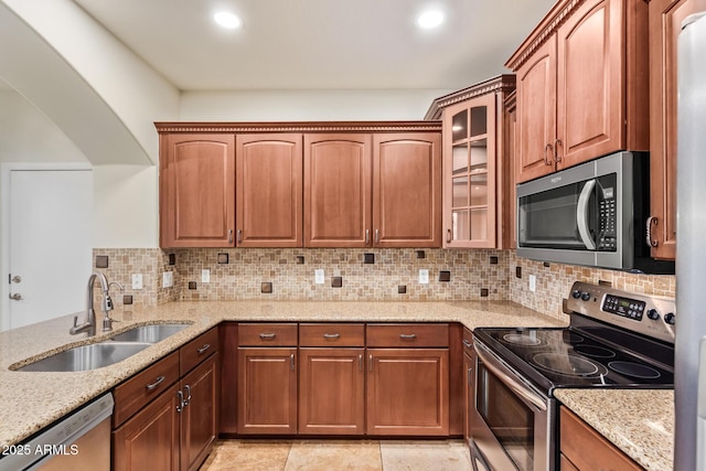 kitchen featuring stainless steel appliances, tasteful backsplash, sink, and light stone counters