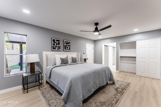 bedroom featuring two closets, ceiling fan, and light hardwood / wood-style flooring