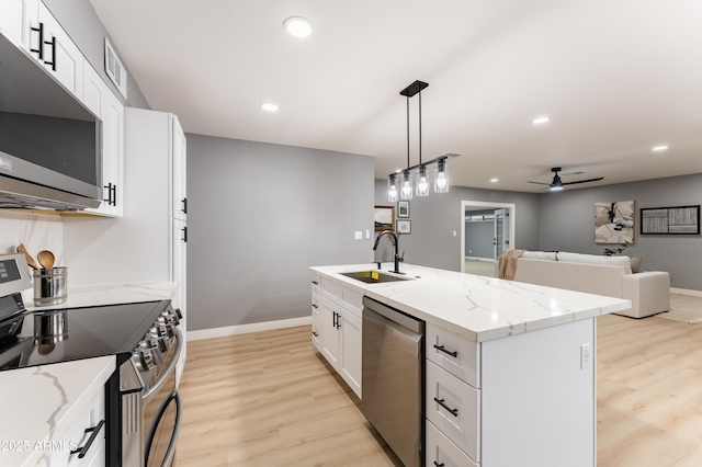 kitchen featuring sink, white cabinetry, decorative light fixtures, appliances with stainless steel finishes, and a kitchen island with sink