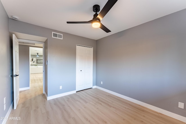 unfurnished bedroom with ceiling fan, light wood-type flooring, and a closet