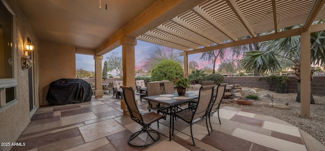 patio terrace at dusk with a grill and a pergola