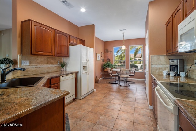 kitchen with sink, white appliances, decorative backsplash, stone countertops, and decorative light fixtures