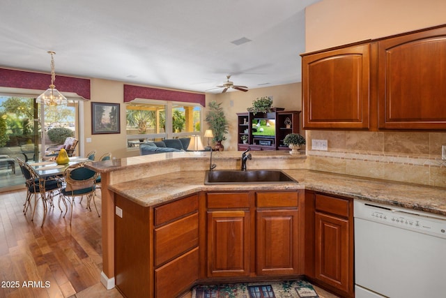 kitchen with pendant lighting, dishwasher, sink, kitchen peninsula, and light hardwood / wood-style flooring