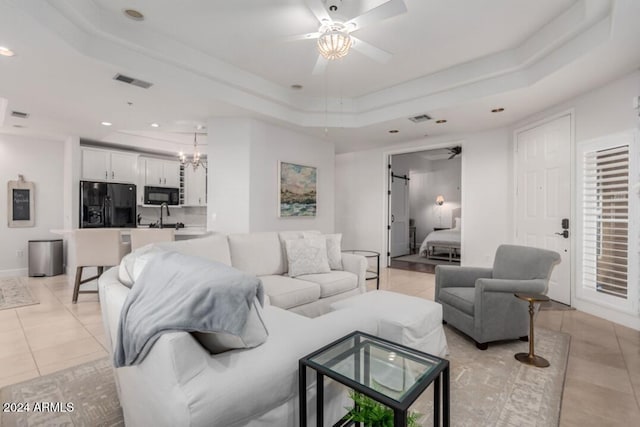 living room featuring light tile patterned flooring, a tray ceiling, and ceiling fan