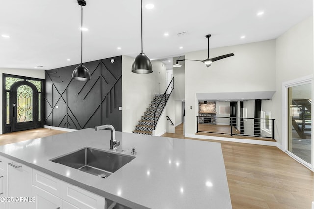 kitchen featuring pendant lighting, white cabinetry, sink, ceiling fan, and light hardwood / wood-style floors