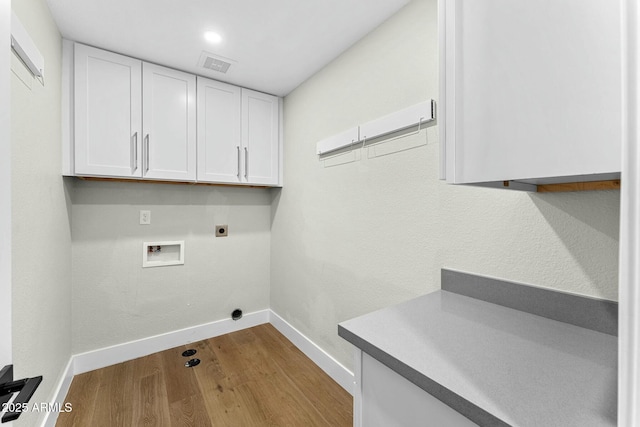 clothes washing area featuring cabinets, electric dryer hookup, washer hookup, and light hardwood / wood-style floors