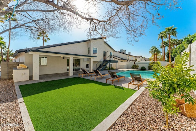 rear view of house with a fenced in pool, a patio, area for grilling, and a yard