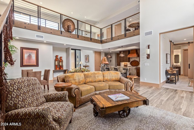 living room featuring a towering ceiling and light hardwood / wood-style floors