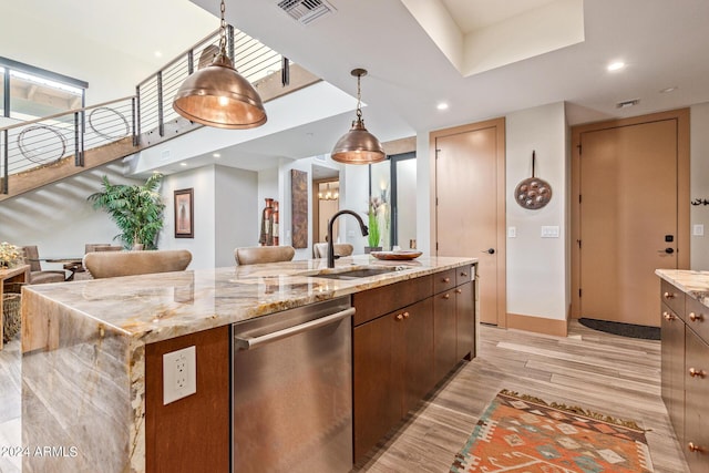 kitchen with dishwasher, sink, light hardwood / wood-style flooring, a spacious island, and decorative light fixtures