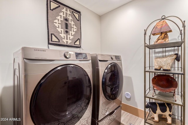 clothes washing area with washing machine and clothes dryer and hardwood / wood-style floors