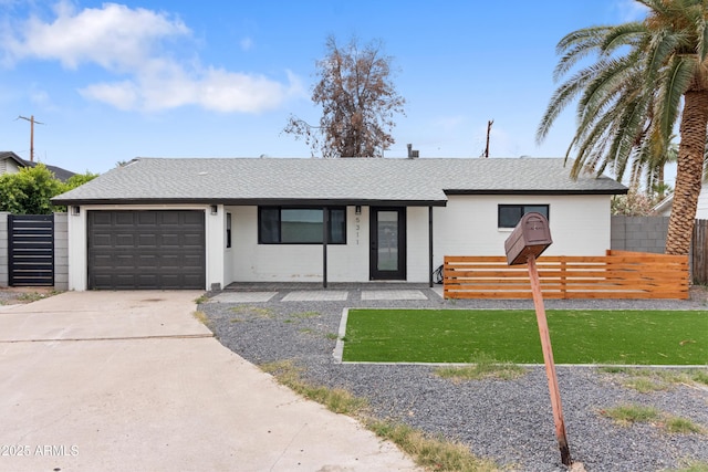 ranch-style house featuring a garage, concrete driveway, and a shingled roof
