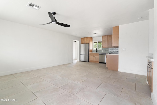kitchen featuring stainless steel appliances, light countertops, a ceiling fan, and backsplash