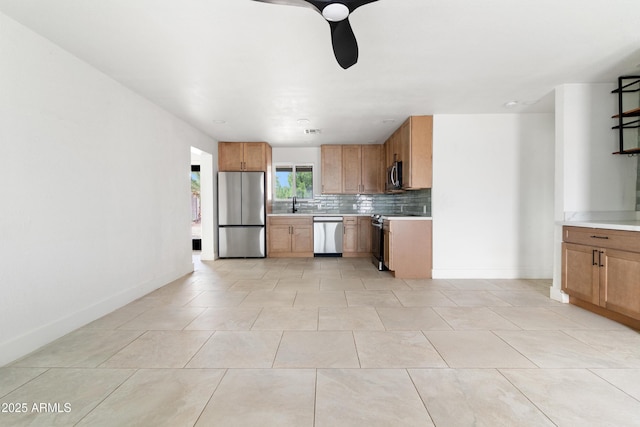 kitchen featuring appliances with stainless steel finishes, backsplash, light countertops, and a sink