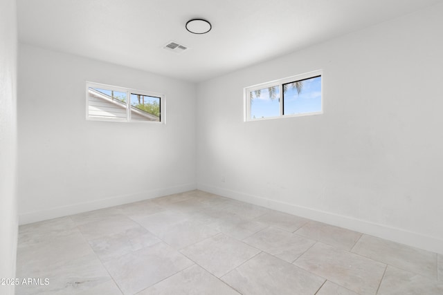 spare room with plenty of natural light, baseboards, and light tile patterned floors