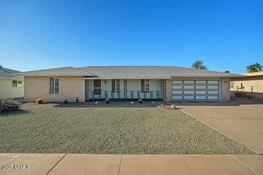 single story home featuring a garage, a front yard, concrete driveway, and a porch