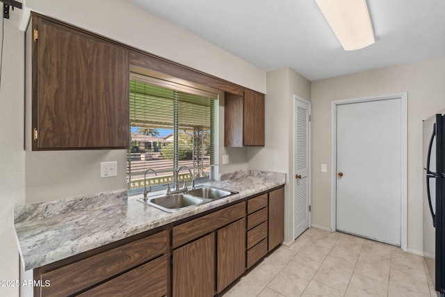 kitchen featuring light tile patterned floors, a sink, baseboards, light countertops, and freestanding refrigerator