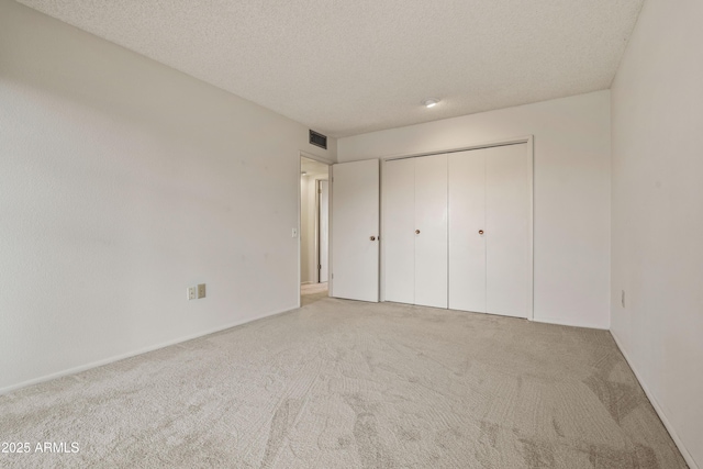 unfurnished bedroom with carpet, a closet, visible vents, and a textured ceiling