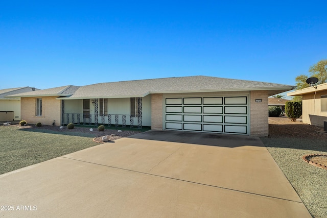 ranch-style house featuring a porch, concrete driveway, brick siding, and an attached garage