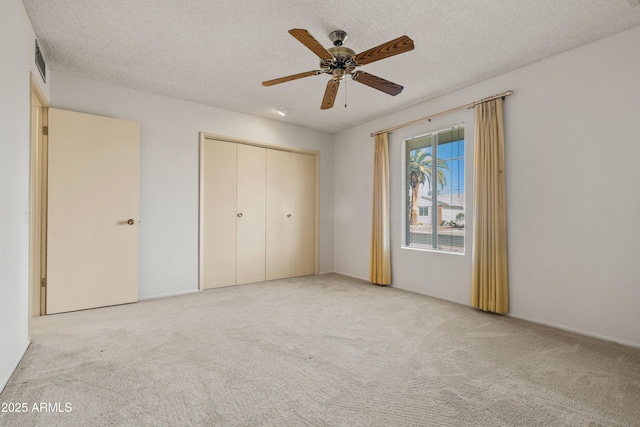 unfurnished bedroom with visible vents, ceiling fan, a textured ceiling, carpet floors, and a closet