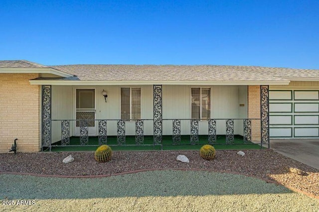 ranch-style home featuring a garage, driveway, a porch, and brick siding