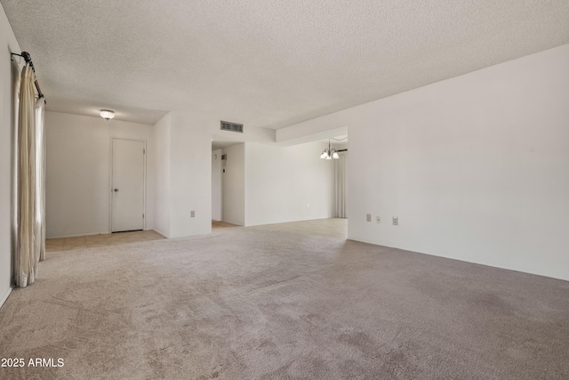 carpeted spare room with visible vents and a textured ceiling