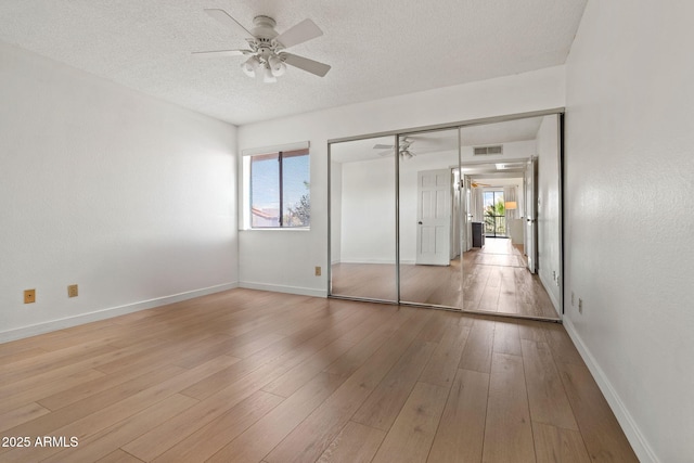 unfurnished bedroom with a textured ceiling, wood finished floors, visible vents, and baseboards