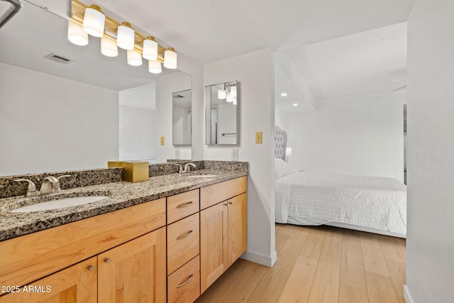 bathroom featuring ensuite bath, visible vents, a sink, and wood finished floors