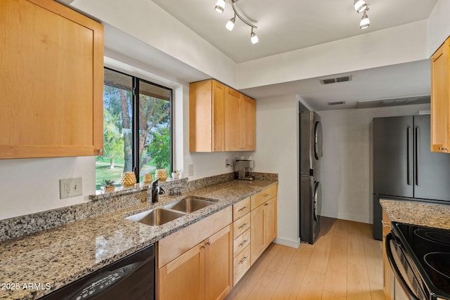 kitchen featuring stacked washer and dryer, visible vents, black appliances, light brown cabinets, and a sink