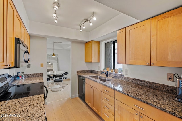 kitchen with light brown cabinetry, appliances with stainless steel finishes, light wood-style floors, a sink, and dark stone counters