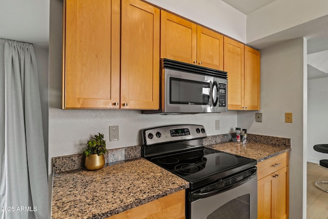 kitchen featuring appliances with stainless steel finishes and dark stone counters