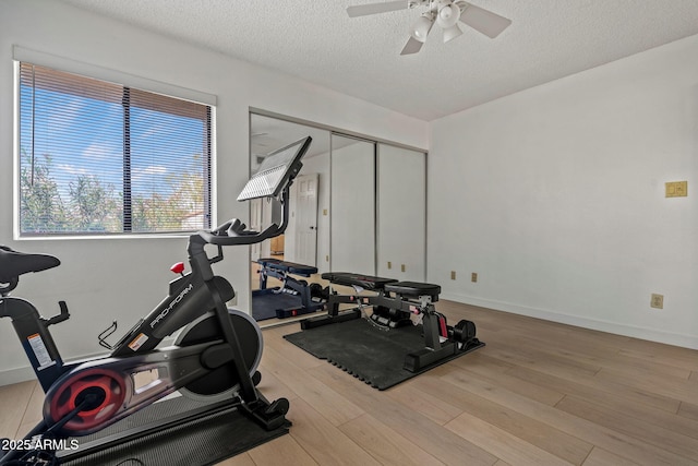 workout room featuring ceiling fan, a textured ceiling, baseboards, and wood finished floors