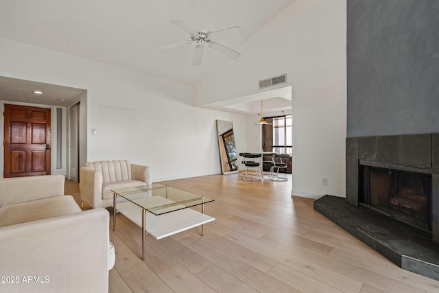 living room with baseboards, visible vents, a ceiling fan, a tile fireplace, and wood finished floors