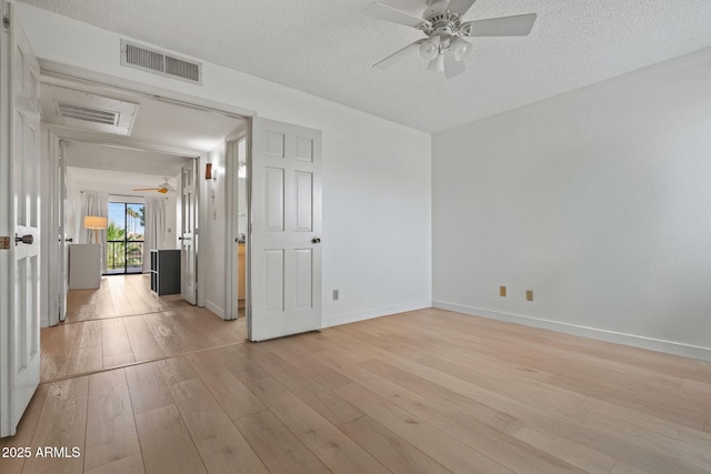 unfurnished room with a textured ceiling, light wood-type flooring, and visible vents