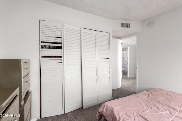 carpeted bedroom featuring a closet, visible vents, and a textured ceiling