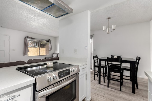 kitchen with white cabinets, open floor plan, light countertops, stainless steel range with electric stovetop, and pendant lighting