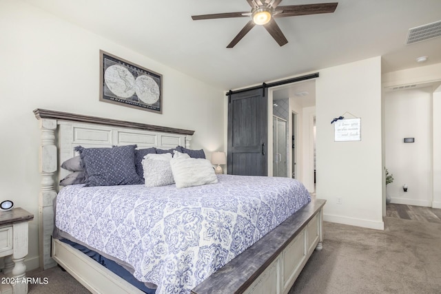 bedroom featuring ceiling fan, visible vents, a barn door, baseboards, and carpet